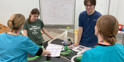 Four students in a veterinary nursing practical class gathered around a training table, reviewing materials and equipment.